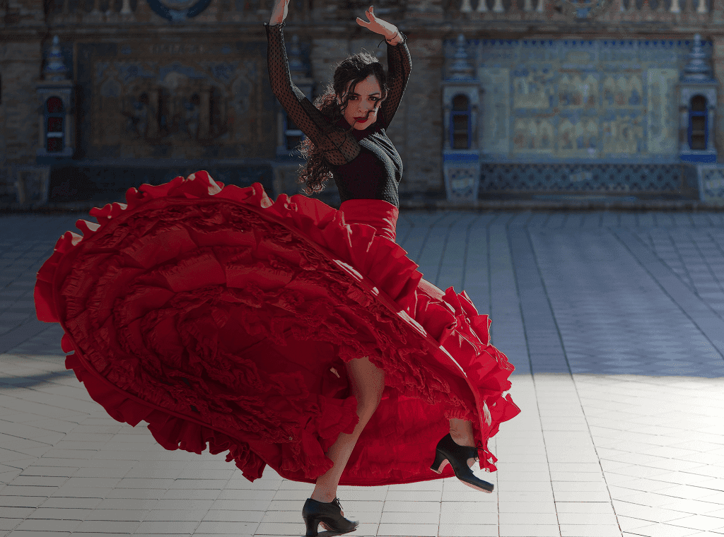 Flamenco dancer spins in front of majestic building backdrop. Overlaid is the Spanish word “bailar” with its English translation, "to dance".